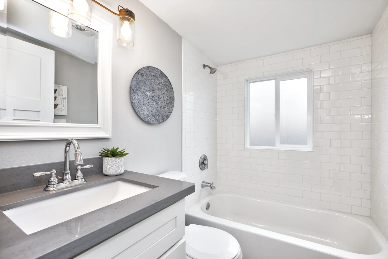 Salle de bain moderne rénovée avec baignoire-douche blanche, robinetterie chromée et carrelage métro blanc