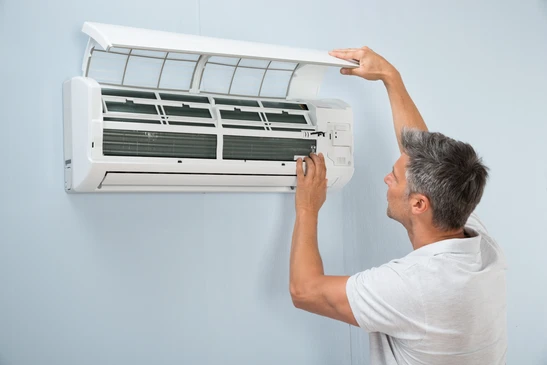 Homme en polo blanc effectuant la maintenance d'un climatiseur mural split system
