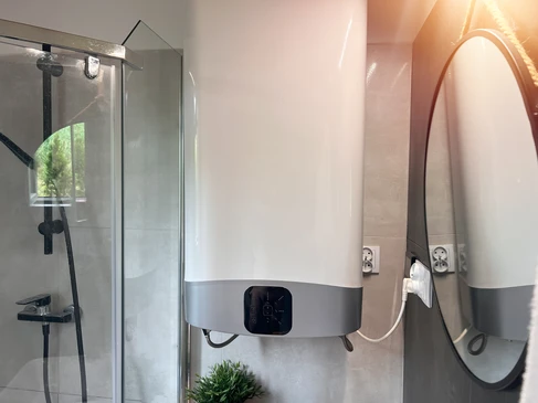 Int&eacute;rieur de salle de bain moderne avec douche &agrave; l'italienne vitr&eacute;e et chauffe-eau &eacute;lectrique mural en cours d'installation