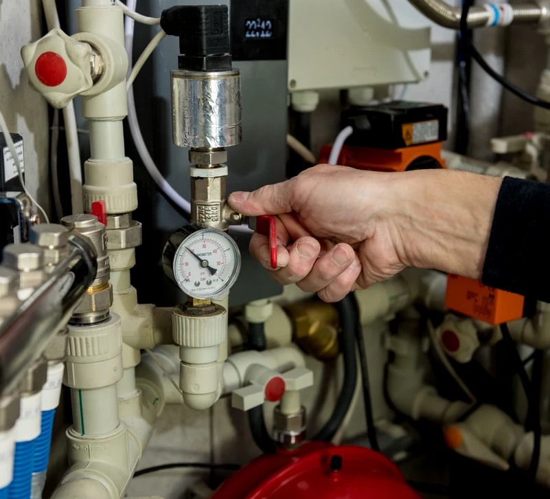 Technicien effectuant maintenance sur système de plomberie industrielle en intérieur