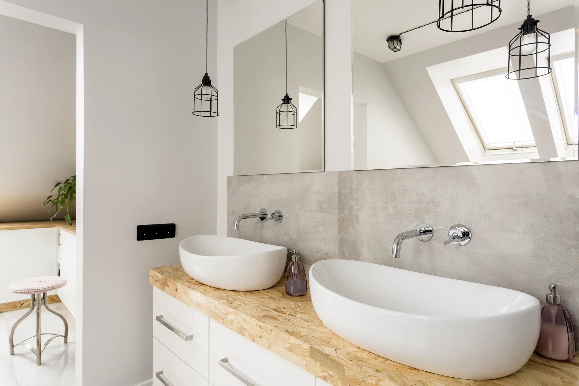 Intérieur salle de bain carrelée grise, plombier installant un lavabo blanc suspendu